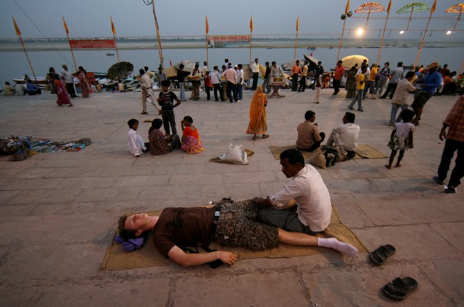 An Indian masseur gives a massage to a tourist on the banks of river Ganges in Varanasi.