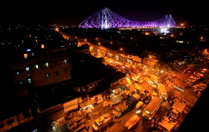 Traffic moves during the evening as the Howrah Bridge is lit up in the background in Kolkata.