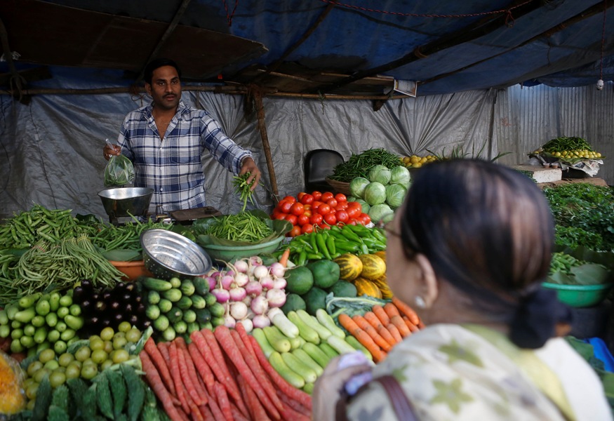 A customer speaks to a vendor while buying vegetables from a street side shop in Mumbai.