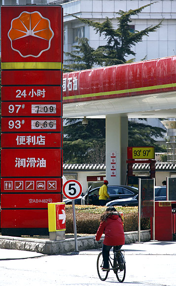 A woman rides her bicycle past a PetroChina petrol station in central Beijing.