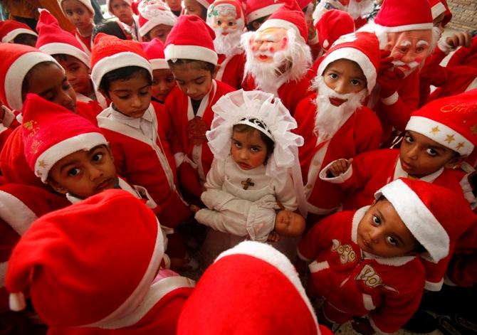 Children dressed in Santa Claus costumes gather around a girl dressed up as Virgin Mary during Christmas celebrations at a church in Chandigarh.