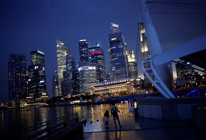 People take photos with the skyline of the financial district of Singapore in the background.