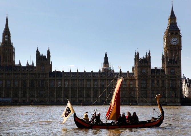 Members of a re-enactment group dressed as Vikings sail a replica Viking Longboat past the Houses of Parliament in London.
