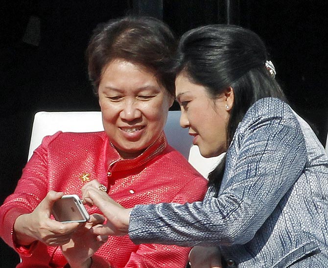 Thailand's Prime Minister Yingluck Shinawatra (R) and Ho Ching, wife of Singapore's Prime Minister Lee Hsien Loong, look at a mobile phone during the ceremonial flag down of ASEAN-India car rally.