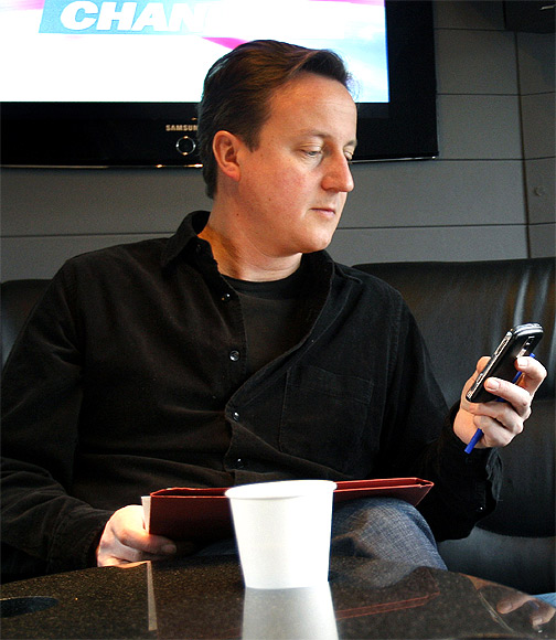 Britain's Prime Minister David Cameron looks at his mobile phone on his bus during an election campaign trip in London.