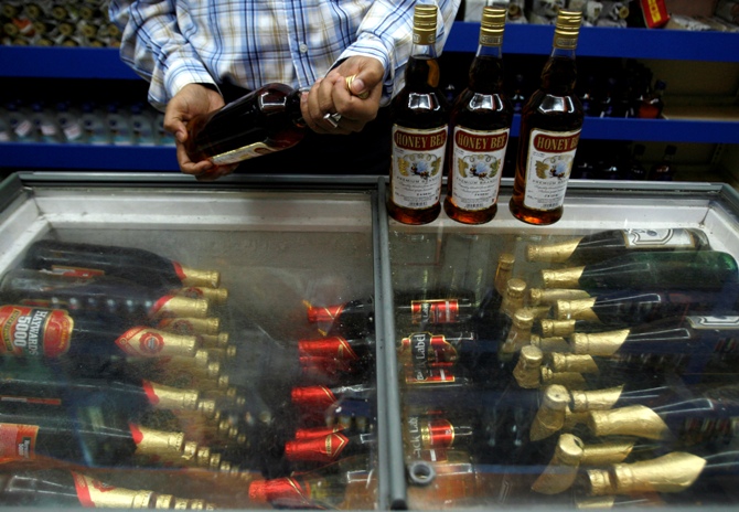 A man checks an alcohol bottle inside a wine shop in Siliguri.