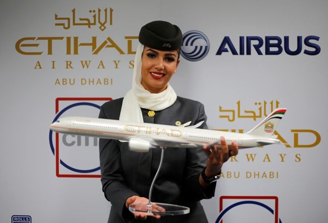 A flight attendant of Etihad Airways holds a model of the Airbus A350 during the Dubai Airshow.