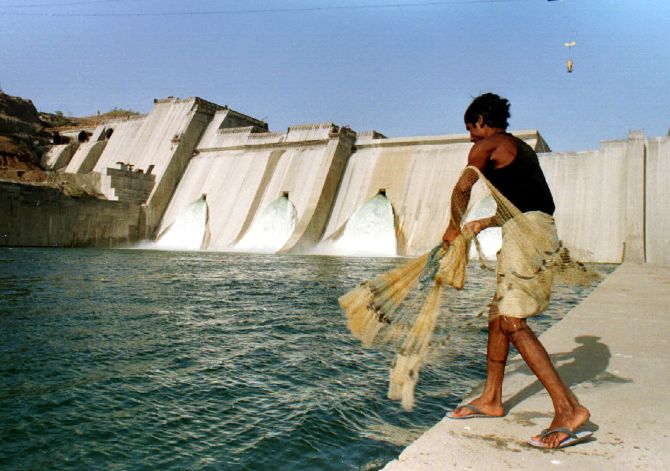 A fisherman casts his net in the waters in front of the half- completed Sardar Sarovar dam on the Narmada river.