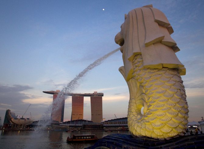 The Merlion statue overlooking the Marina Bay area spouts water as the Marina Bay Sands resort and casino is pictured in the background.