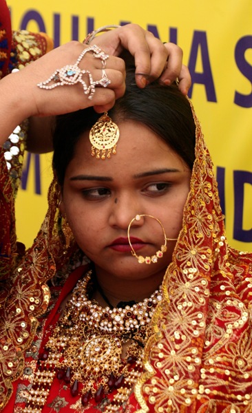 A bride is bedecked with jewellery during a mass wedding ceremony in Ahmedabad.