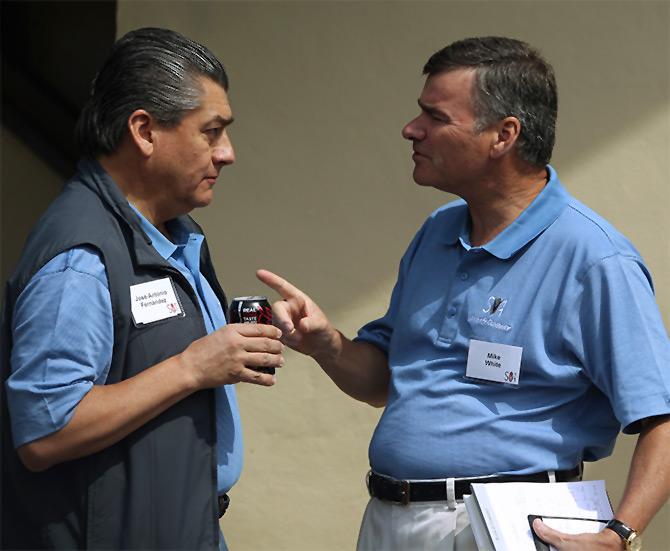 DirecTV chairman, president and chief executive Mike White (R) gestures while speaking with FEMSA chairman and chief executive Jose Antonio Fernandez.