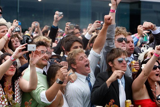 Race-goers celebrate as they watch jockey Corey Brown ride Shocking to victory in the Melbourne Cup at Flemington racecourse in Melbourne.