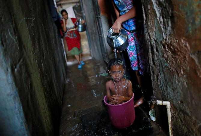 Four-year-old Manjunath takes a bath while sitting inside a bucket outside his house in a slum in Mumbai.