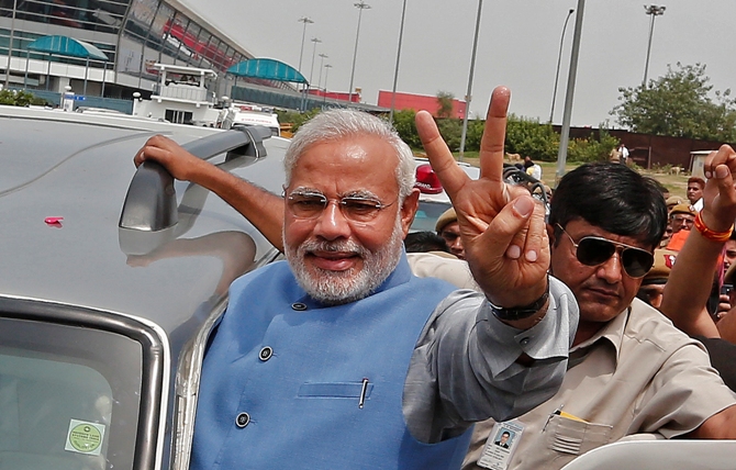 Prime Minister Narendra Modi gestures towards his supporters from his car.