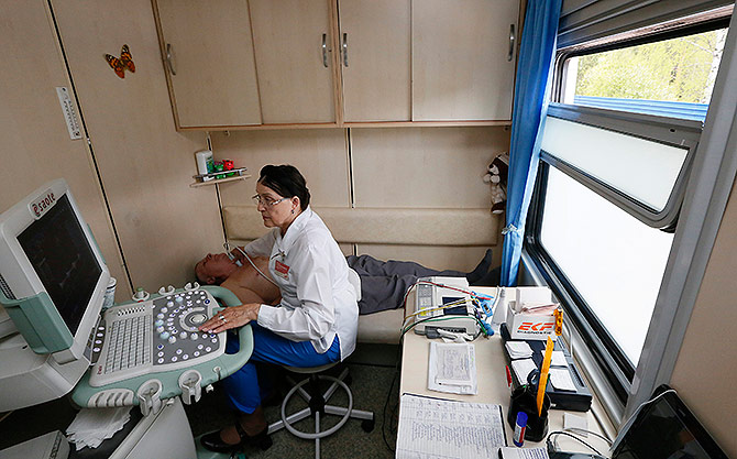 A doctor assists a patient inside the Doctor Voino-Yasenetsky Saint Luka train.