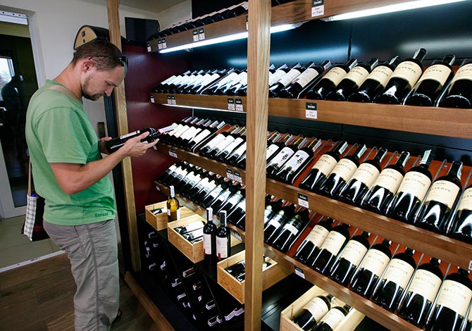 A man holds at a bottle of wine at a store of an industrial complex.