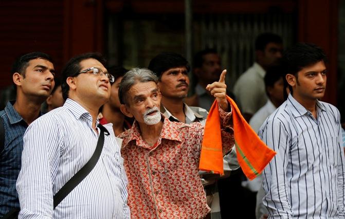 People look at a screen across the road displaying the election results on the facade of the Bombay Stock Exchange.