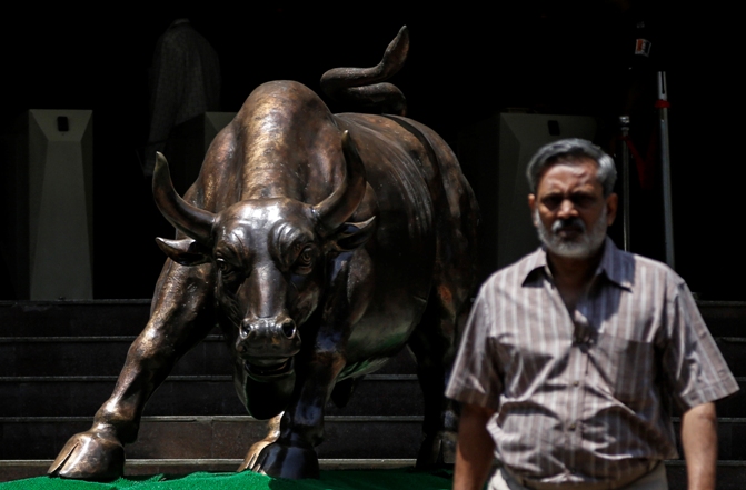 A bronze bull sculpture is seen as an employee walks out of the Bombay Stock Exchange.