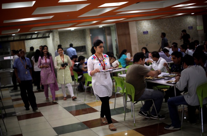 An employee carries her lunch at a cafeteria inside Tech Mahindra office building in Noida.