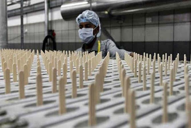 A worker monitors an automatic candy making machine inside an ice cream factory. 