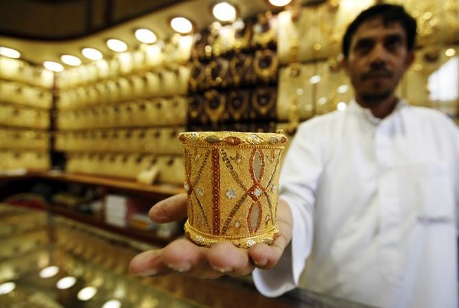 A jeweller displays gold bangle in a jewellery shop.