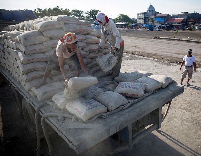 Porters move sacks of cement at a construction site.