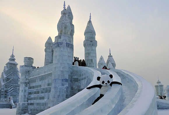 An employee wearing a panda costume slides down from an ice sculpture during the Harbin International Ice and Snow World festival in Harbin, Heilongjiang province, China.
