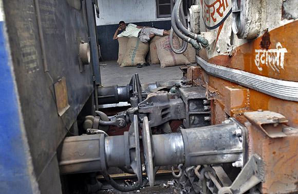 A passenger rests on sacks lying on the platform next to a train as he waits for electricity to be restored at a railway station in New Delhi