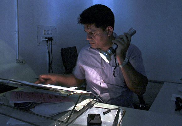An officer reads documents with the help of a torch at the driving registration and license authority office during a power-cut in Chandigarh