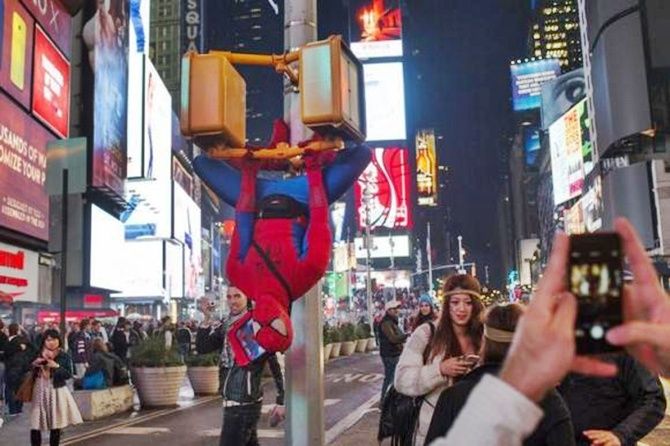  A man in a Spider-Man costume hangs upside down from digital cross walk signs in Times Square during Halloween, in New York. 