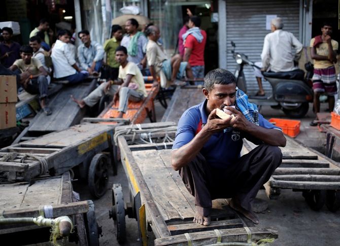 A labourer drinks tea as he sits on a handcart parked at a wholesale grocery market in the old quarters of Delhi