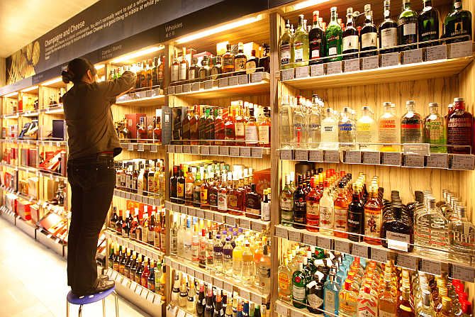 An employee arranges bottles of whisky at a supermarket in Shanghai, China.