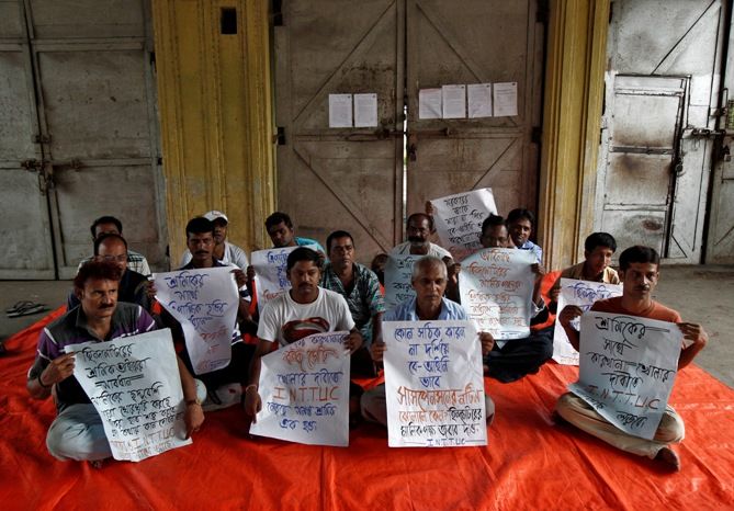 Employees hold placards as they sit on a protest outside Hindustan Motors Ltd's Uttarpara plant near Kolkata.