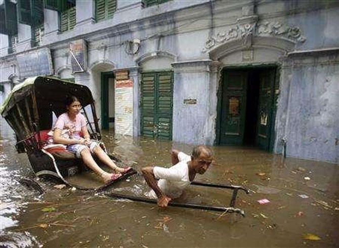 Image: A rickshaw puller transports a girl through a flooded street in Kolkata. Photograph: Jayant Shaw/Reuters