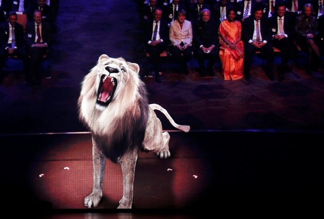 A lion is projected on a screen as German Chancellor Angela Merkel (top right row, 2nd left) and India's Prime Minister Narendra Modi attend the opening ceremony of the world's largest industrial technology fair, the Hannover Messe, in Hanover April 12, 2015. Wolfgang Rattay/Reuters
