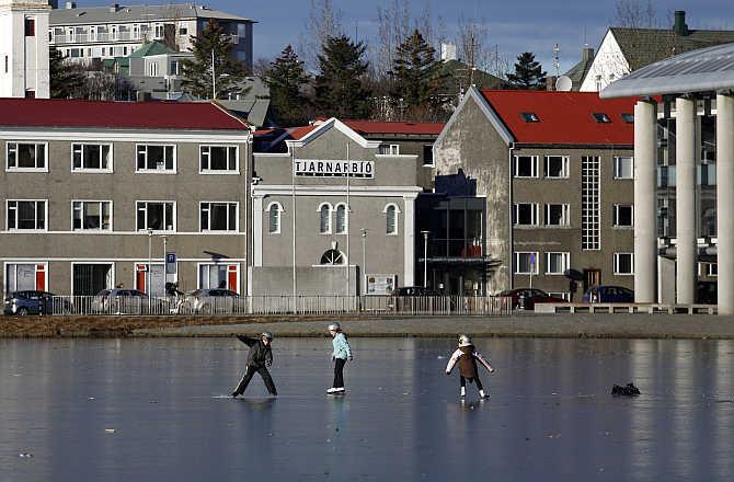 Children skate on the ice of the frozen Tjoernin lake in central Reykjavik, Iceland