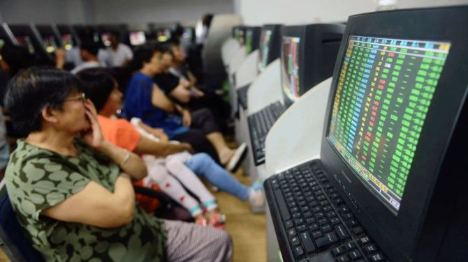 Investors sit in front of computer screens showing stock information at a brokerage house in Qingdao. 
