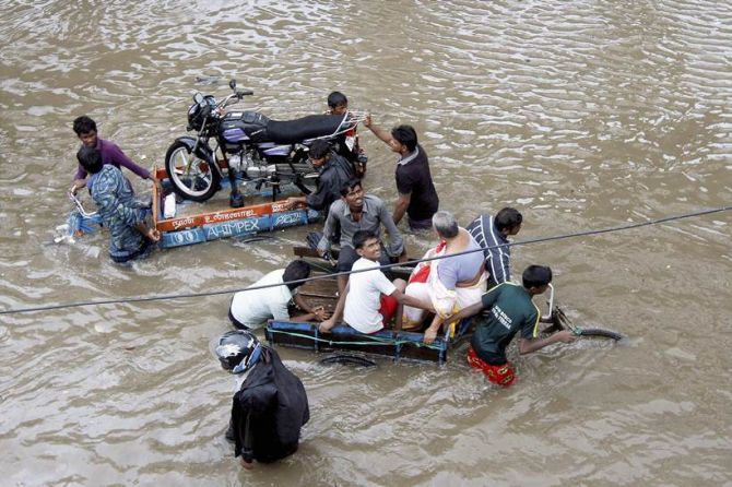 People help a man carry his two-wheeler on a cycle cart as they wade through a waterlogged subway in Chennai.