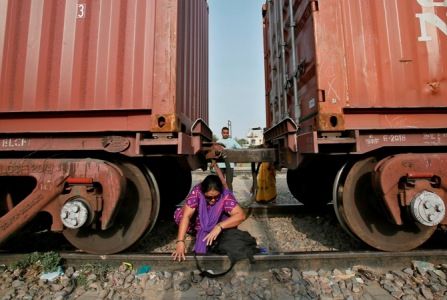 A woman crosses under the carriages of a parked goods train. Anindito Mukherjee/Reuters