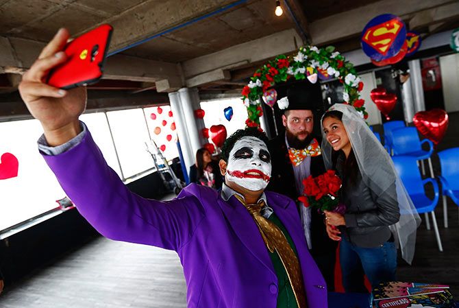 A man dressed as comic book character The Joker takes a selfie.