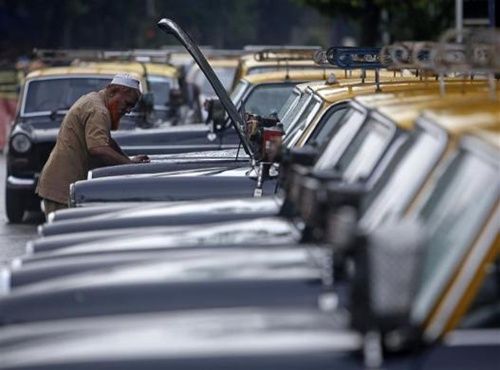 A taxi driver inspects the engine of his Premier Padmini taxi at a taxi park in Mumbai.