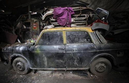 A de-registered Premier Padmini taxi is pictured covered in dust with love hearts etched on its windows inside a scrapyard in Mumbai.