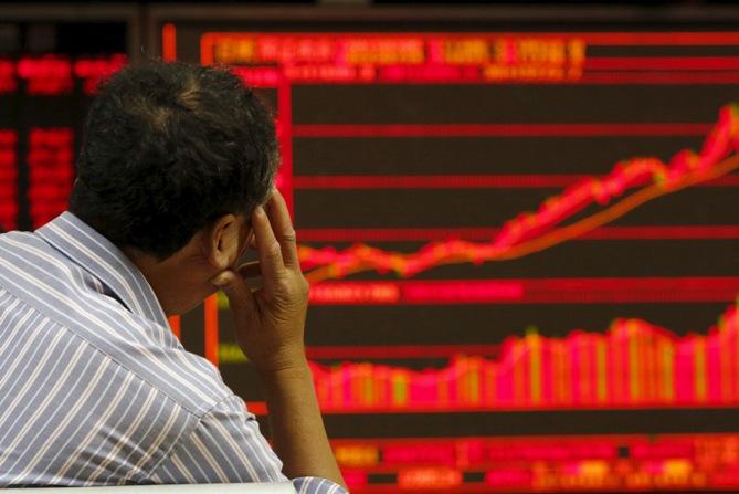 An investor watches an electronic board showing stock information at a brokerage office in Beijing, China, July 9, 2015. 