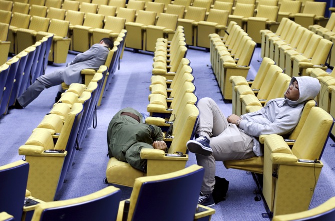 Reporters sleep in the press conference room of the European Council during an euro zone leaders summit in Brussels, Belgium, July 13, 2015. 