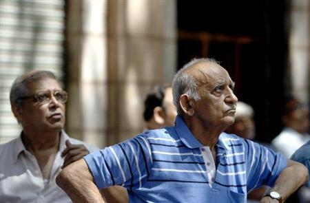 People look at a large screen displaying India's benchmark share index on the facade of the Bombay Stock Exchange (BSE) building in Mumbai. 