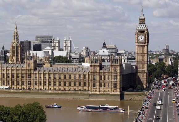 Traffic on the road and the Thames passes the Houses of Parliament in London