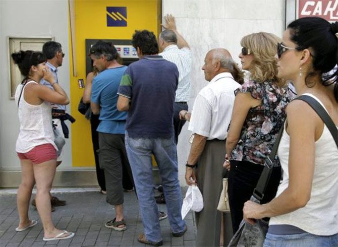 People wait to withdraw cash from an ATM on the island of Crete, Greece. Photograph: Stefanos Rapanis/Reuters