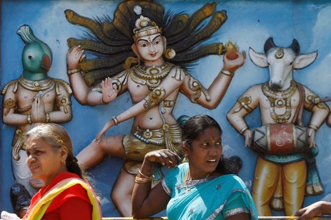 Hindu devotees walk slowly in a queue past an idol of a Natraja as they throng to a temple to offer prayers