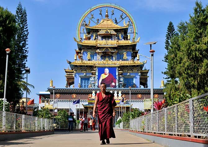 A Tibetan Buddhist monk walks in front of the Golden Temple inside the Nyingmapa Monastery in Bylakuppe, southwest of Bengaluru, previously known as Bengaluru