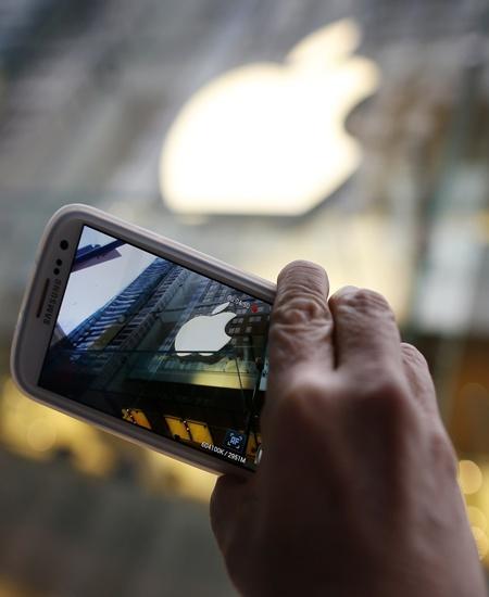 A man clicks the Apple logo with his Samsung mobile.